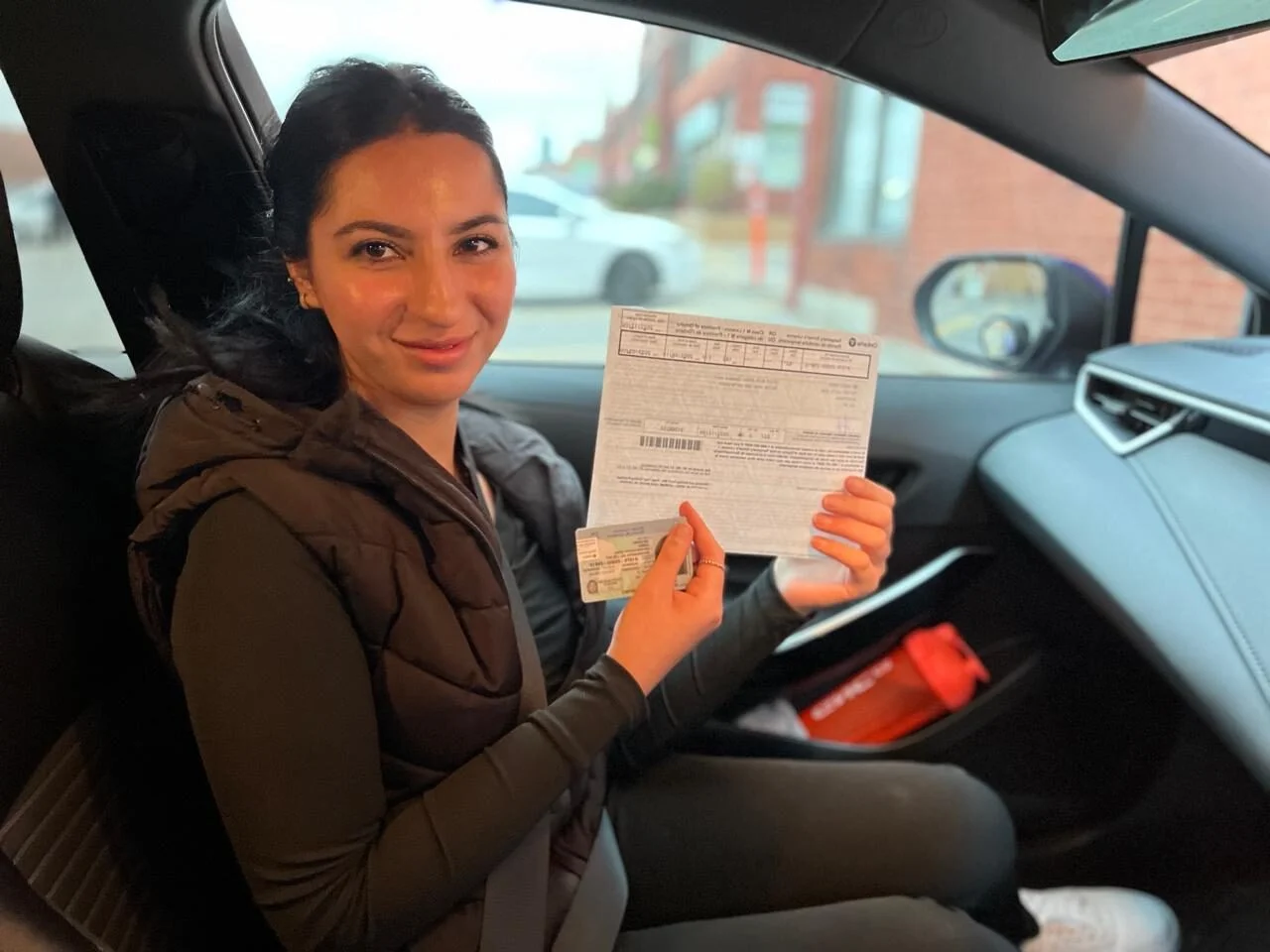 Student holding driving license inside car after driving lessons Oakville, Downtown Oakville.