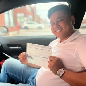 Joyful learner holding driving license inside vehicle after driving classes Mississauga, Meadowvale area.