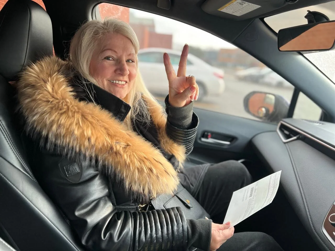 Student proudly showing license inside car with driving instructor Mississauga, Port Credit neighbourhood.
