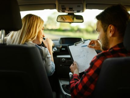 Instructor helps woman to drive the car